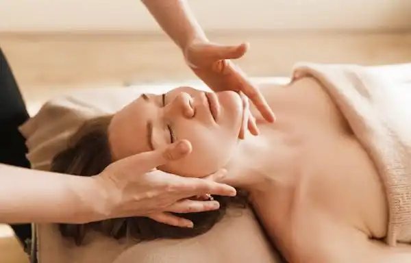 Woman laying on table with white towel wrapped on her getting an adaptive massage